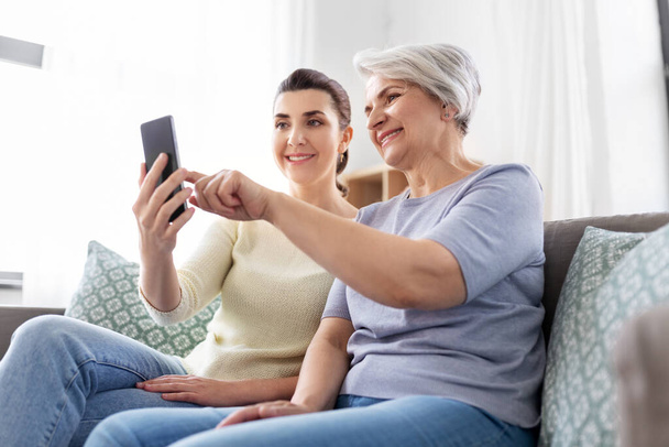 daughter and senior mother with smartphone at home - Zdjęcie, obraz