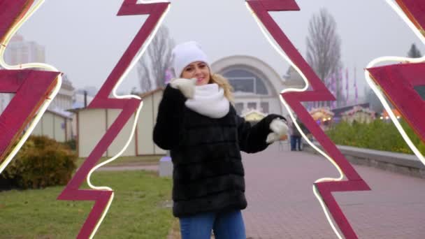 Positieve vrouw in warm witte hoed, sjaal, wanten dansen, glimlachen buiten - Video