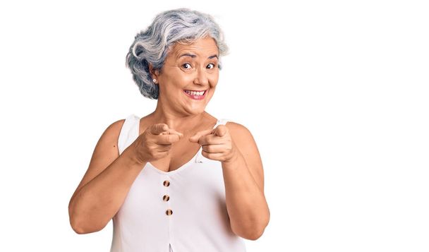Oudere vrouw met grijs haar in casual kleding wijzende vingers naar camera met gelukkig en grappig gezicht. goede energie en vibes.  - Foto, afbeelding