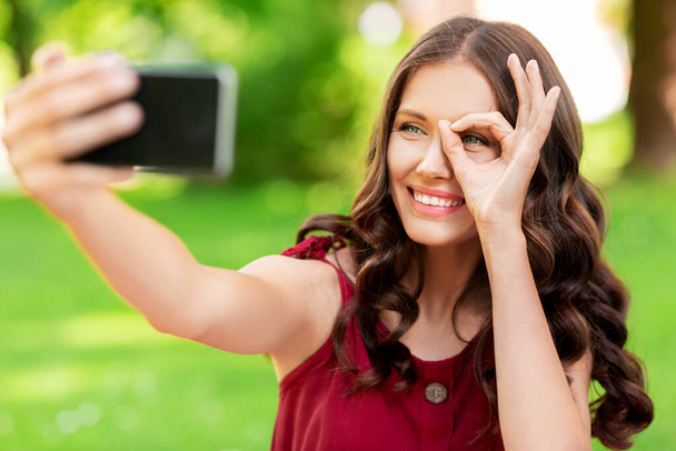 happy woman with smartphone taking selfie at park - Fotoğraf, Görsel