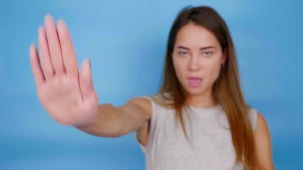 Bella donna seria in grigio T-shirt tiene fuori il palmo della mano alla fotocamera, dice stop - Filmati, video