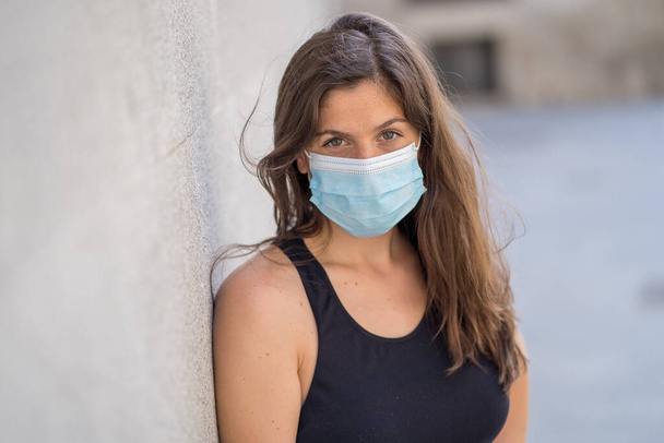 Young woman wearing surgical mask on face in public spaces. Coronavirus spreading protection mask protective against influenza viruses and diseases. Positive image of New Normal life after COVID-19 - Foto, Imagen