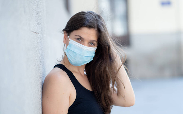 Young woman wearing surgical mask on face in public spaces. Coronavirus spreading protection mask protective against influenza viruses and diseases. Positive image of New Normal life after COVID-19 - Foto, Imagen