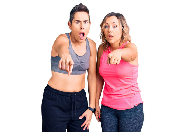Couple de femmes portant des vêtements de sport pointant mécontent et frustré à la caméra, en colère et furieux contre vous  - Photo, image