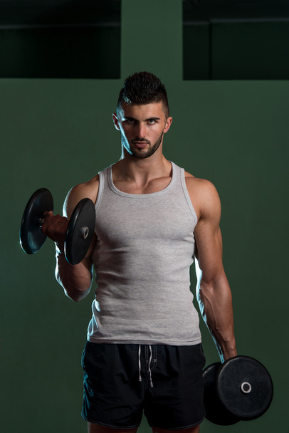 Young Man Lifting Dumbbell In Gym - Foto, afbeelding