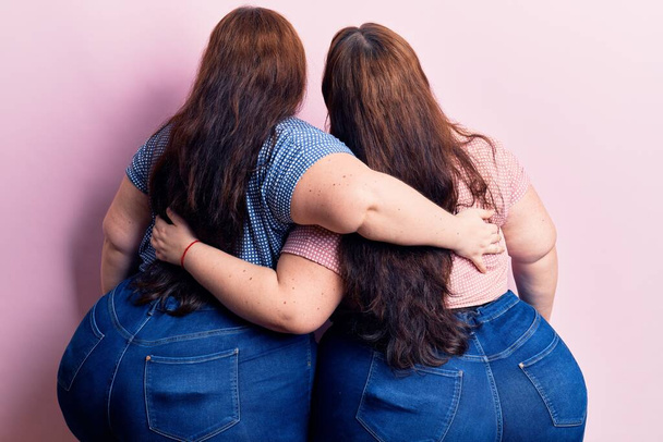 Junge Plus-Size-Zwillinge in lässiger Kleidung umarmen sich glücklich und positiv von hinten. Selbstliebe und Selbstfürsorge  - Foto, Bild