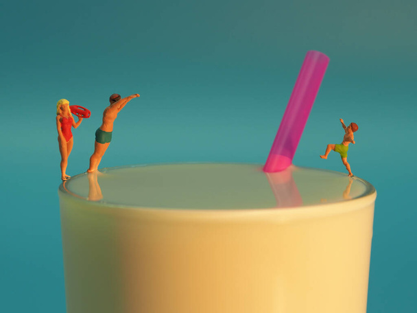 Glas Milch mit Strohhalm und drei Miniaturfiguren - Foto, immagini
