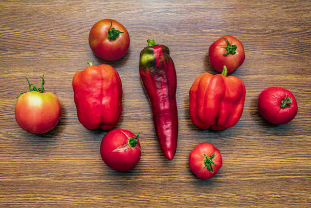Три стручки красного перца и шесть помидоров лежат на кухонном столе. - Фото, изображение