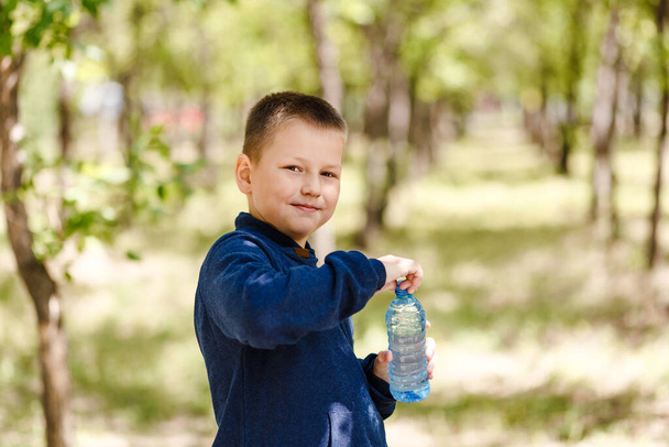 smiling boy with a plastic bottle of drinking water outdoors - Valokuva, kuva