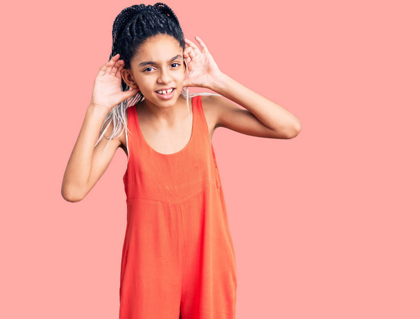 Aranyos afro-amerikai lány alkalmi ruhában, aki mindkét kezét fülgesztusokra hallgatja, és pletykákra kíváncsi. hallási probléma, süket  - Fotó, kép