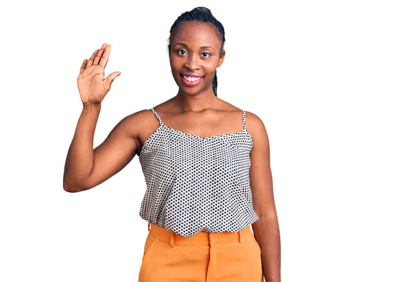 Молода афроамериканка, одягнена в повсякденний одяг, показує і вказує вгору пальцями номер п'ять, посміхаючись впевнено і щасливо.  - Фото, зображення