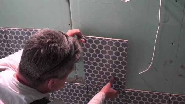 Industrial tiler constructor trabajador que trabaja con piso de baldosas por el que se encuentra en nueva casa plana - Metraje, vídeo