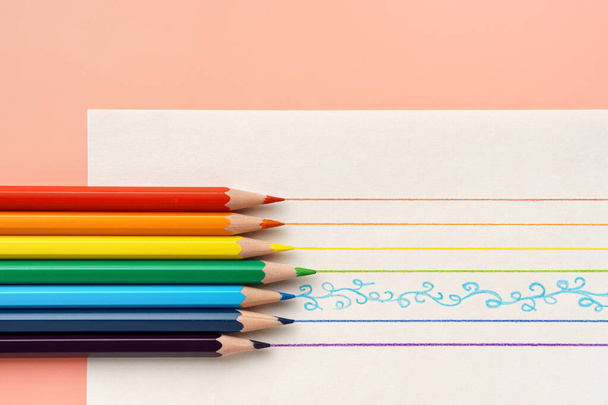 Colorful pencils on white paper and multicolored lines on yellow background - Photo, Image