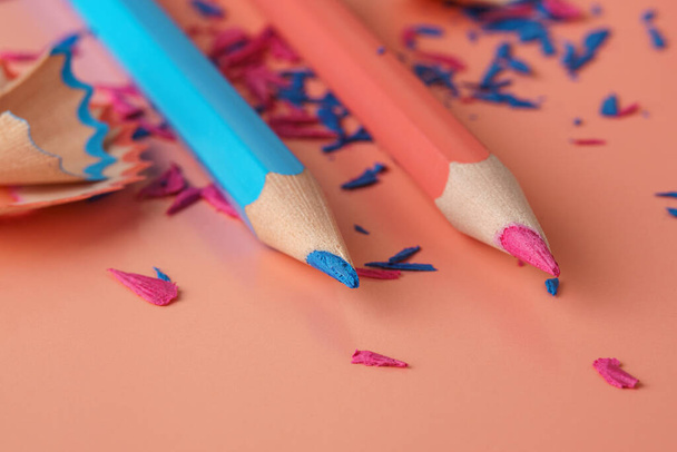 Blue and pink pencils and colored wooden and graphite pencils shavings on pink surface - Фото, зображення