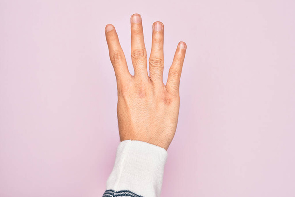 Ruka bělocha mladý muž ukazující prsty přes izolované růžové pozadí počítání číslo 4 ukazující čtyři prsty - Fotografie, Obrázek