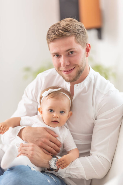 Young good looking male with his baby daughter both looking at the camera. - Fotoğraf, Görsel