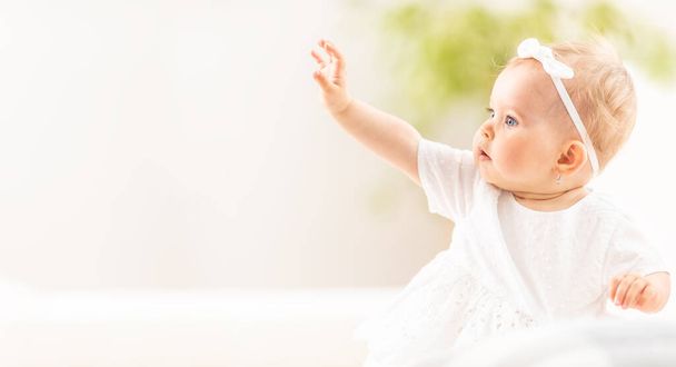 Banner view of a small baby girl reaching with one hand into the air. - Foto, Imagen
