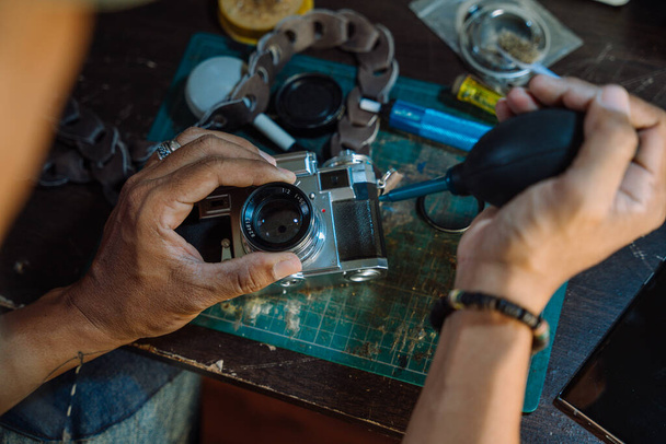 Um homem consertar a câmera de filme e limpar a poeira na lente, em seguida, montar toda a peça em conjunto
. - Foto, Imagem