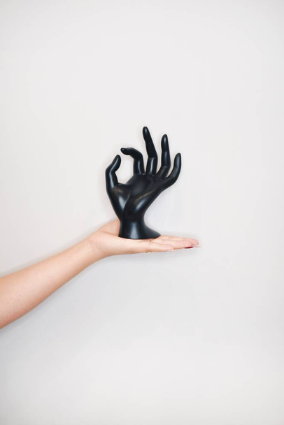 A woman's hand holds a plastic hand. Manicurist. Model for manicure. - Foto, afbeelding