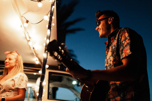 Party men are singing their friends at night near a camper van - Photo, image