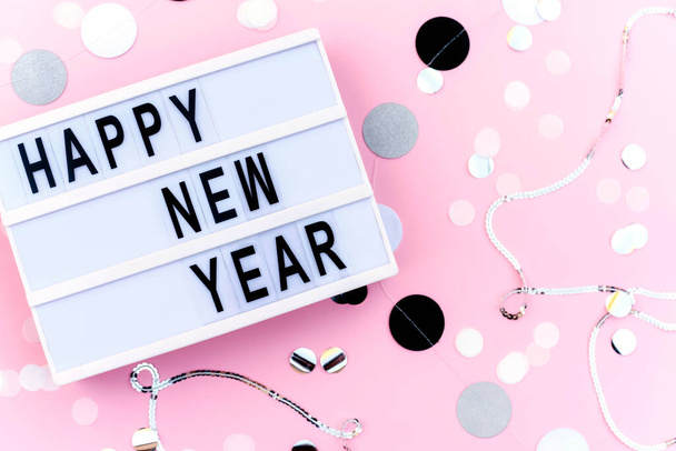 Üzerinde "Mutlu Yıllar" yazan pembe renkli bir ışık kutusu. Yeni yıl konsepti. Yeni Yıl. - Fotoğraf, Görsel