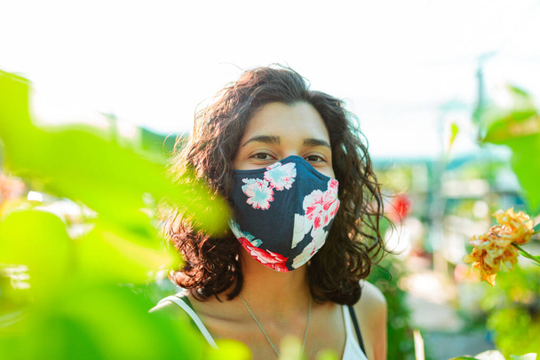 Vrouw met gezichtsmasker tuinieren in kas covid-19 - Foto, afbeelding