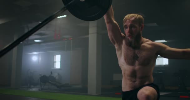 Slow motion: Man doing Single-Arm Landmine Squat-to-Press exercise. Young man lifting barbell with light weights at gym - Footage, Video
