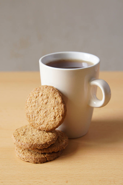 A closeup shot of the tasty cookies with a cup of coffee on a wooden surface - Fotó, kép