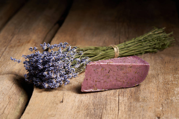 A piece of lavender cheese with bunch of fresh lavender flowers on rough wooden planks - Foto, afbeelding