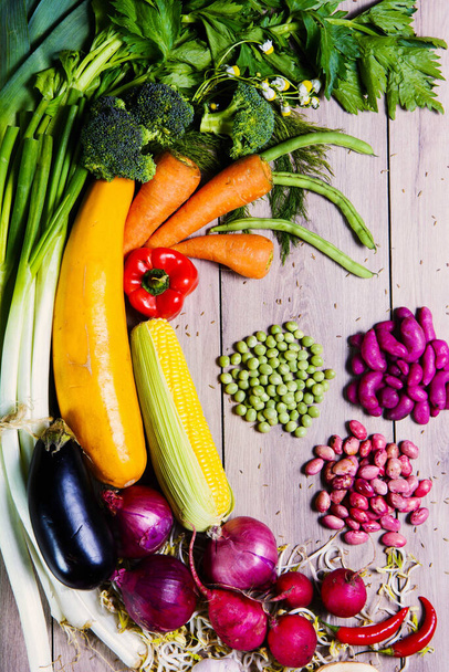 A vertical overhead shot of colorful different vegetables and beans on a wooden surface - Foto, Imagem