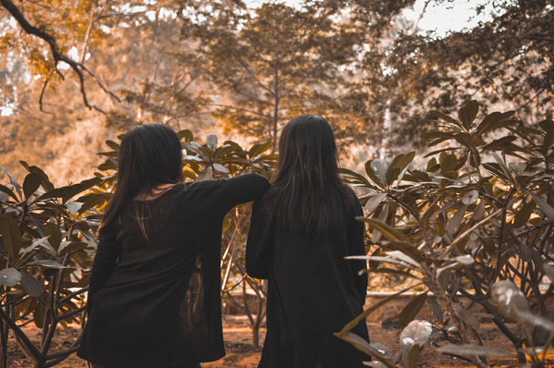 A selective focus shot of two young brunettes dressed in black enjoying the beautiful nature - Φωτογραφία, εικόνα