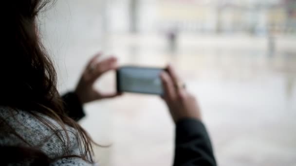 Fiatal nő okostelefonnal fényképez nedves európai város - Felvétel, videó