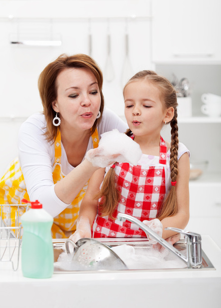 Woman and little girl washing dishes - having fun with the foam - Фото, изображение