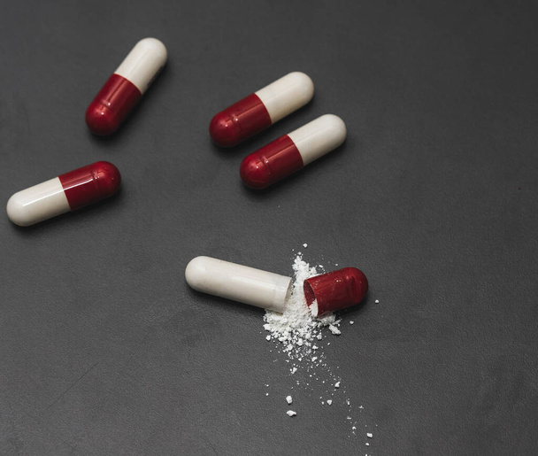 A high angle shot of the red and white capsules on a grey surface - Photo, image
