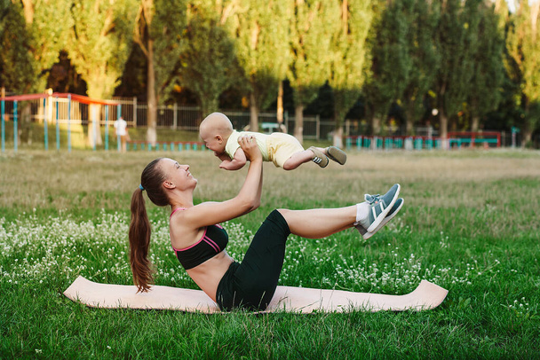 Jovem mãe treino na natureza gramado de grama com bebê
  - Foto, Imagem