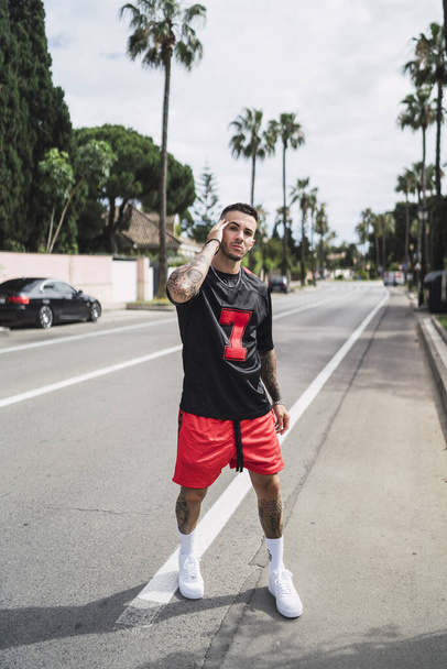 A vertical shot of an athletic young man with tattoos posingwalking on the street - 写真・画像