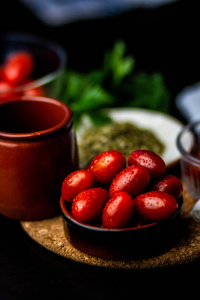 Una toma vertical de tomates junto a verduras, condimentos y una taza marrón - Foto, Imagen