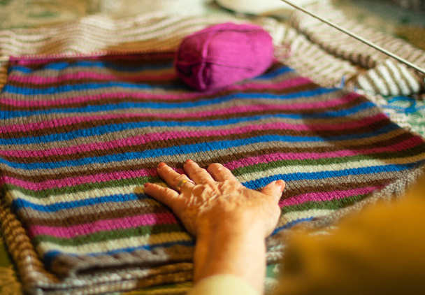 A close up shot of a grandmother knitting a sweater from colorful thread yarns - Foto, Imagen