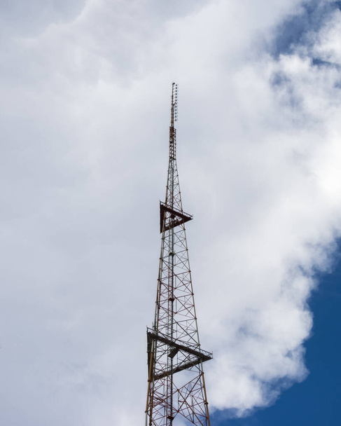 Bulutlu bir arka planı olan uzun bir telefon kulesinin dikey görüntüsü. - Fotoğraf, Görsel
