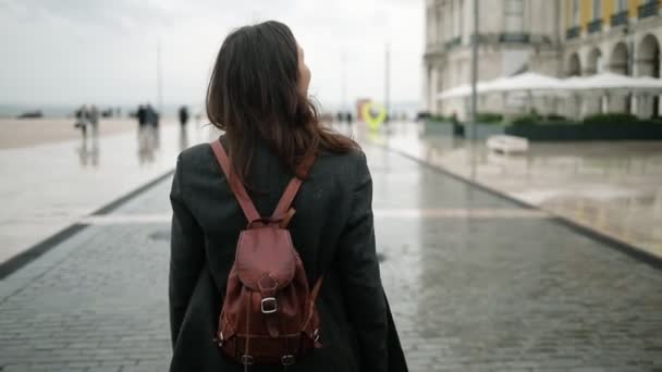 Вид сзади на красивую туристическую девушку в пальто и рюкзаке - Кадры, видео
