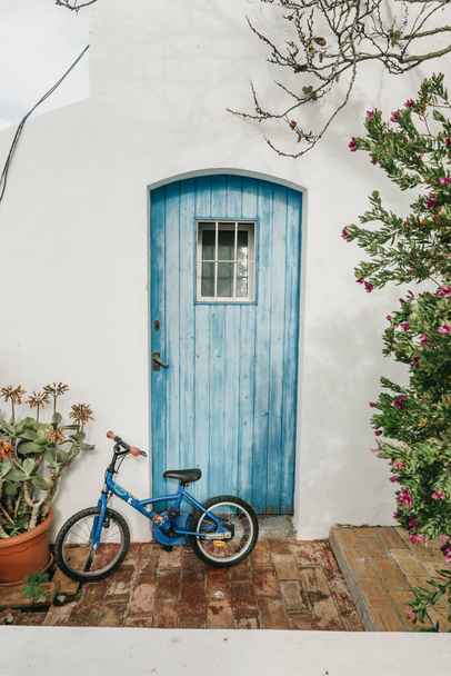 A vertical shot of an old bike leaning against a wall near a wooden door - Фото, зображення