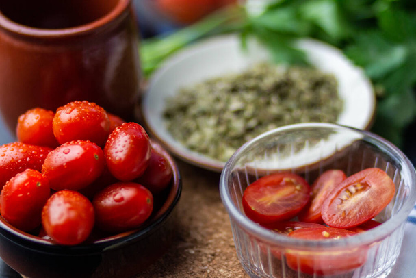 A closeup shot of tomatoes next to greens, condiments and a brown cup - Foto, Imagen