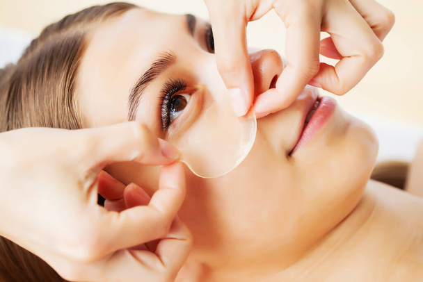 Kosmetikerin im Wellness-Salon bewirbt sich unter Augenklappen - Foto, Bild