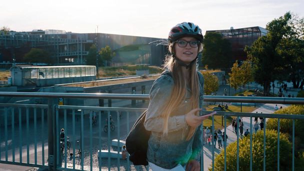 若い幸せな女性が橋の上でスケートし、スマートフォンを使用しての肖像画.  - 写真・画像