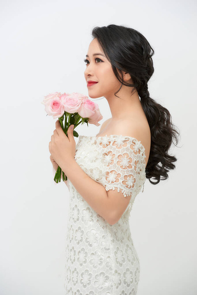 白い背景に花束を保持結婚式のドレスで美しい若い花嫁。スペースのコピー. - 写真・画像
