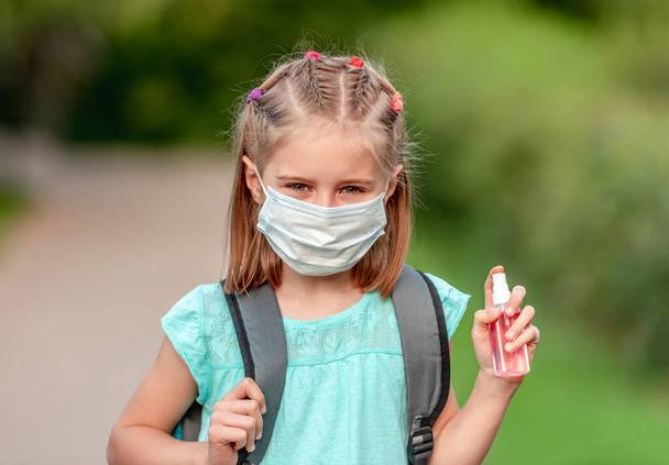 School girl in mask holding sanitizer - Fotoğraf, Görsel