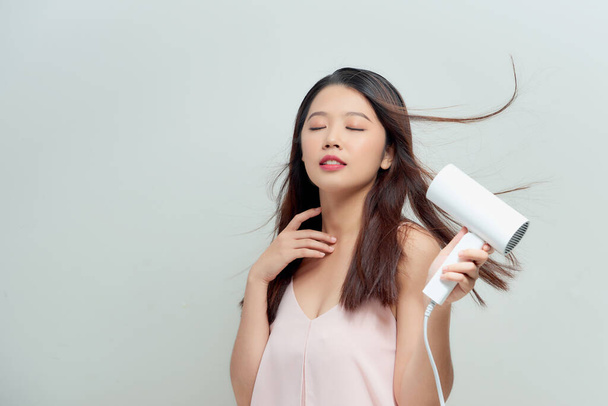 Portrait of attractive girl with black hair using hairdryer - Photo, Image