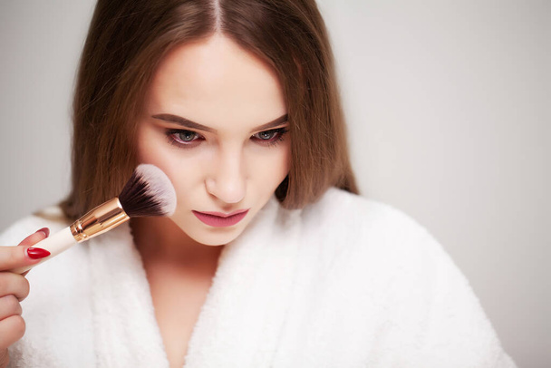 Beautiful woman using brush for daily makeup in bathroom - Foto, Bild