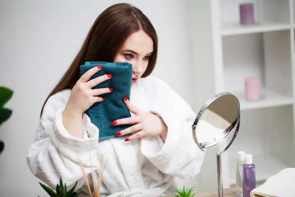 Mujer joven limpiándose la cara con toalla en el baño. - Foto, Imagen