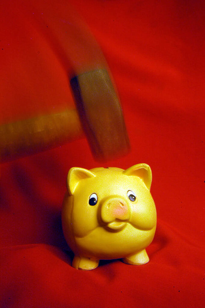σπάσιμο ενός κουμπαρά με ένα σφυρί, σε κόκκινο φόντο - Φωτογραφία, εικόνα